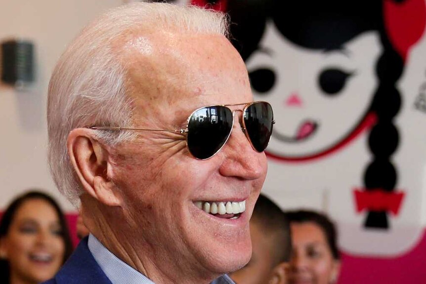 Democratic US presidential candidate Joe Biden smiles while eating icecream