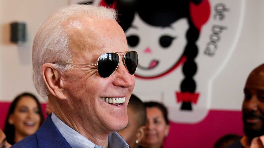 Democratic US presidential candidate Joe Biden smiles while eating icecream