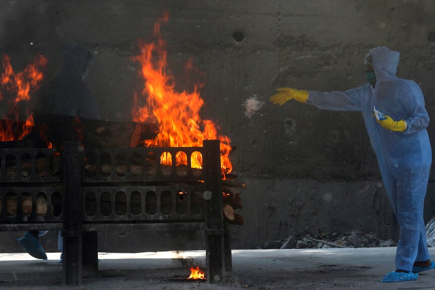 A municipal worker in PPE performs last rites at the cremation of a COVID-19 victim in Mumbai, India.