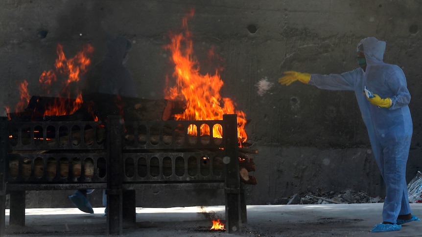 A municipal worker in PPE performs last rites at the cremation of a COVID-19 victim in Mumbai, India.