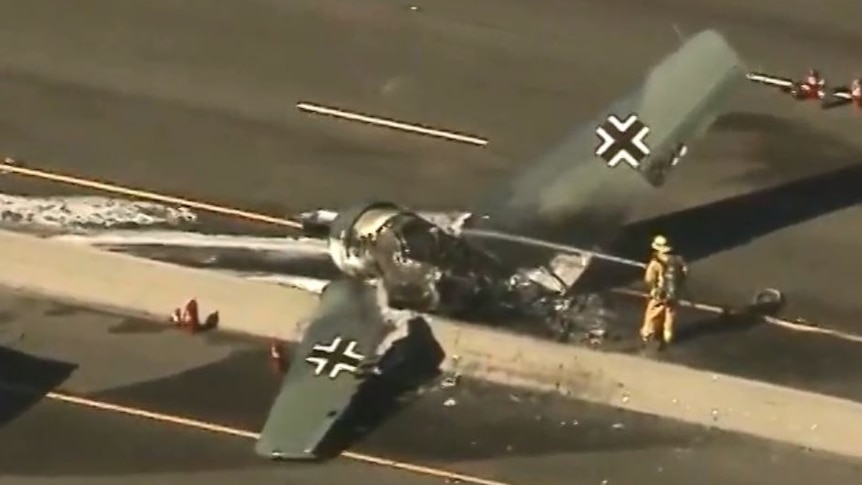 Fire fighters put out a fire on a plane crashed on a highway centre divider