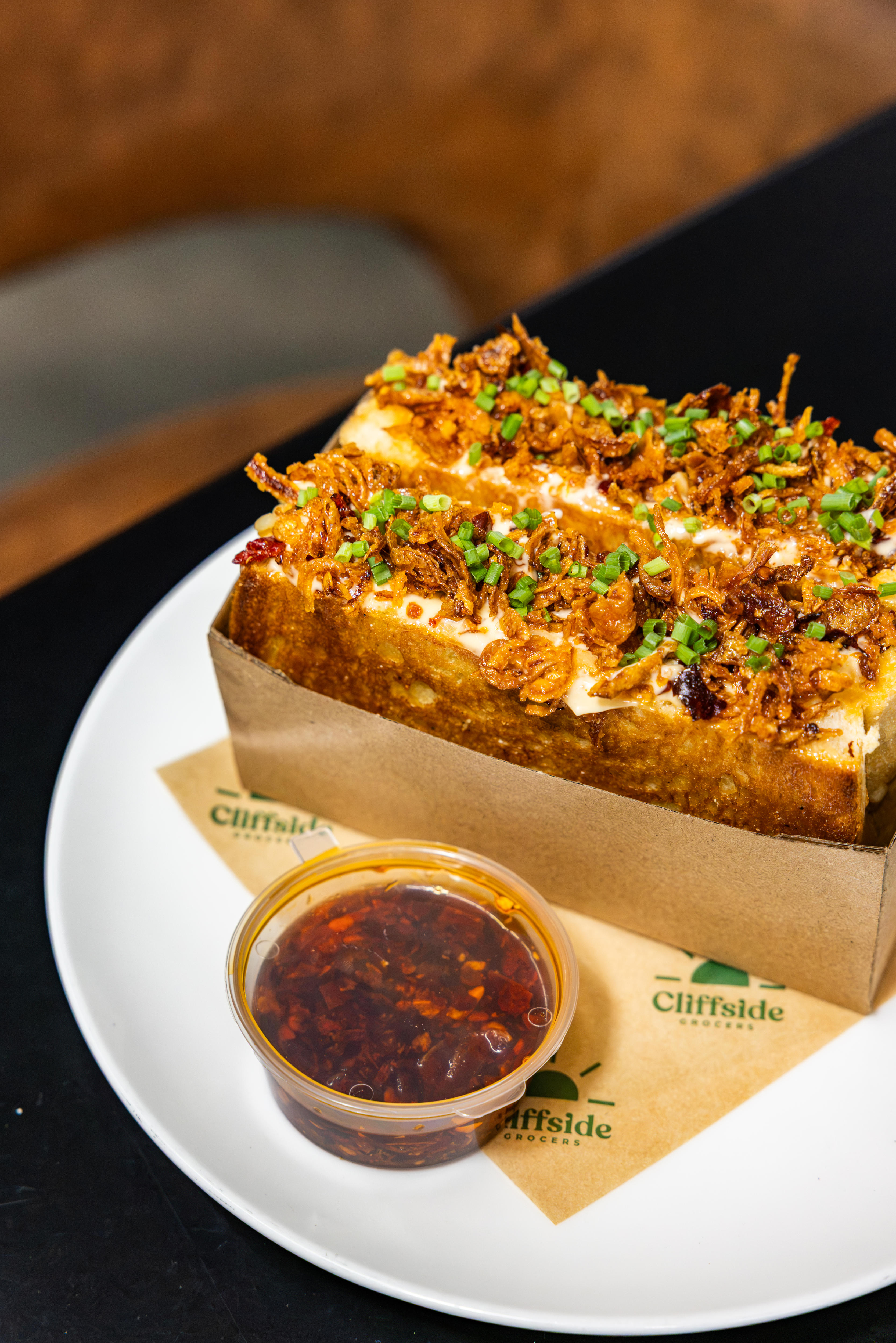 A toasted sandwich cut in half with laksa ingredients showing through the top.