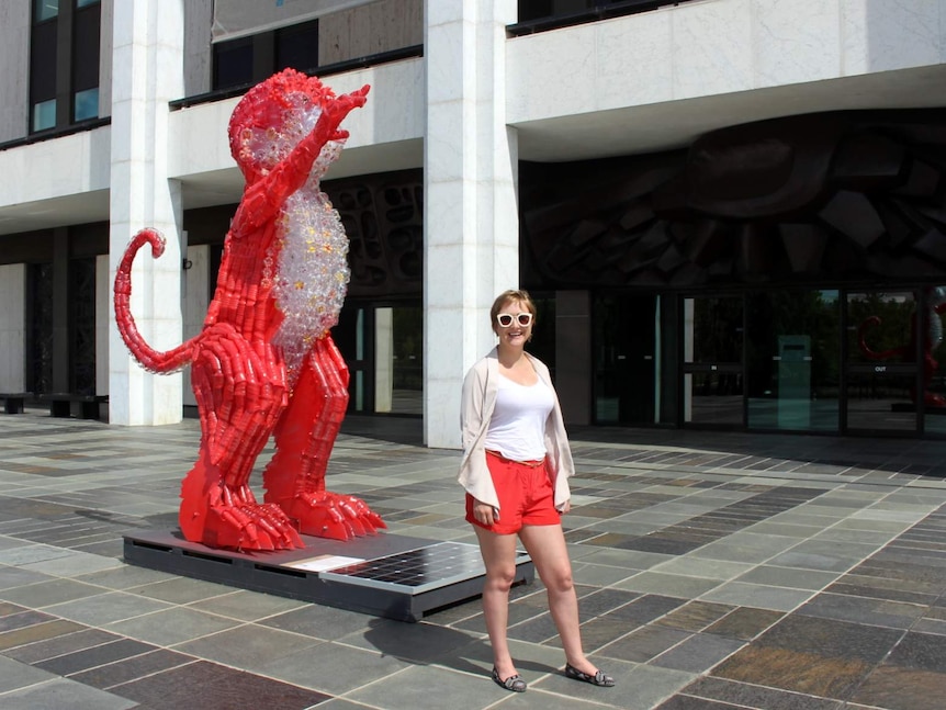 Claire Tracey with her plastic bottle monkey sculpture at the National Library of Australia.
