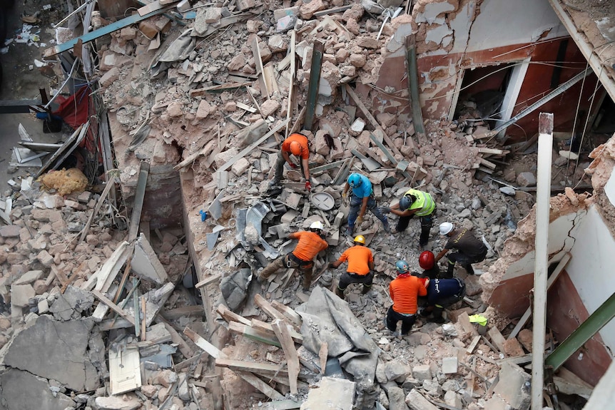 Rescuers search in the rubble of a collapsed building as seen from an aerial view.