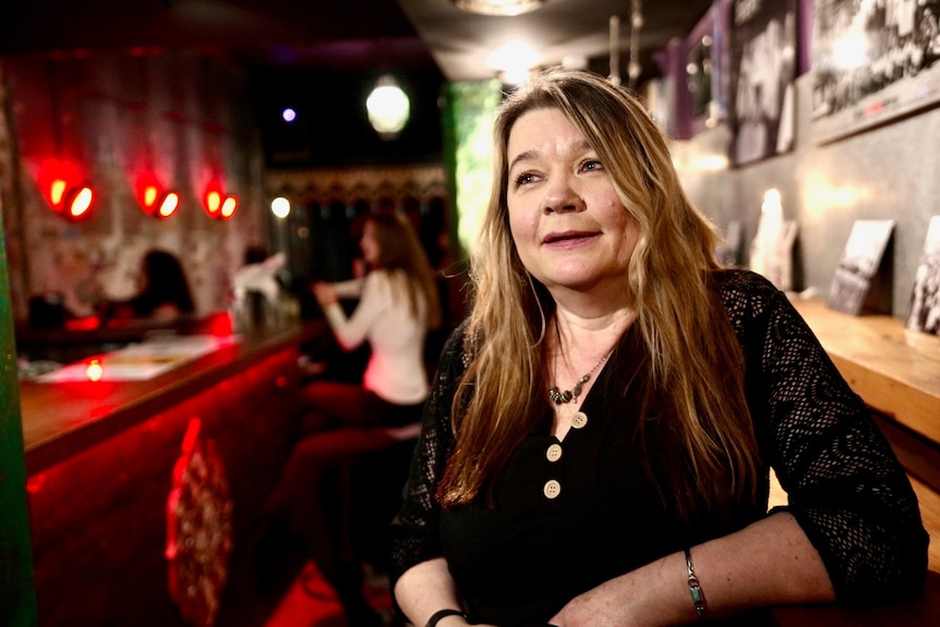 Caroline Buckingham sits on a stool inside the small bar she owns.