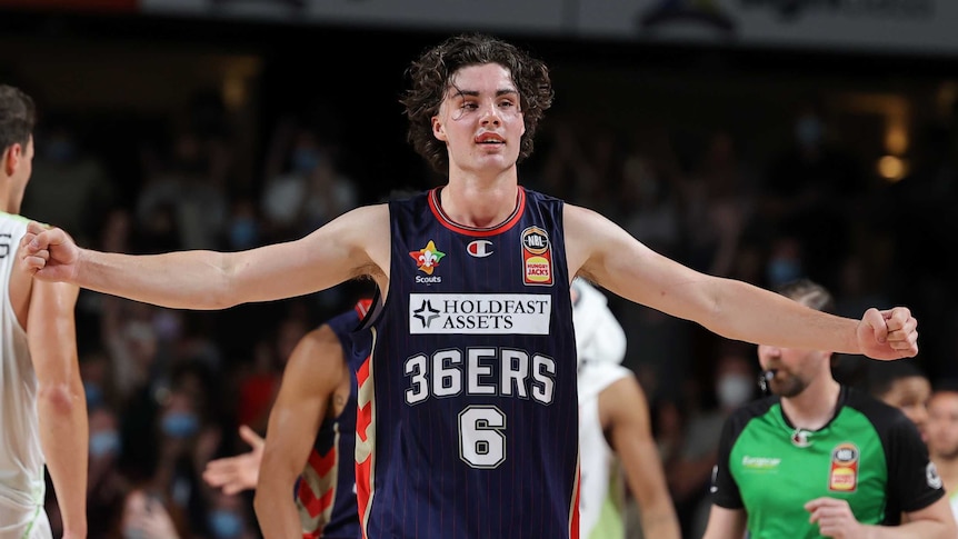 Josh Giddey spreads his arms with fists clenched during an NBL game for the Adelaide 36ers.