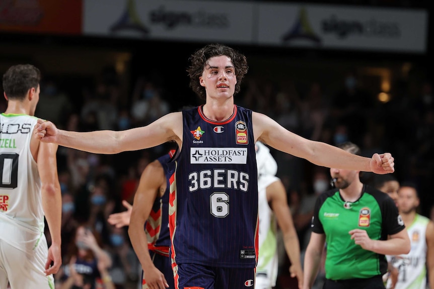Josh Giddey spreads his arms with fists clenched during an NBL game for the Adelaide 36ers.