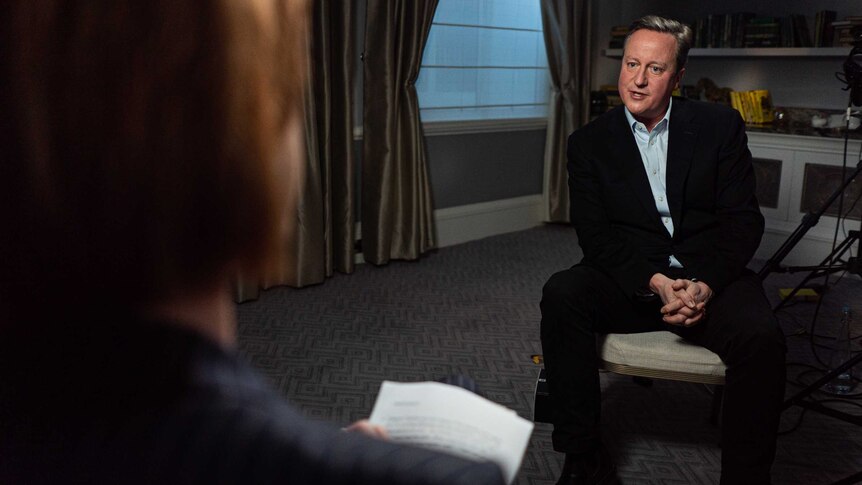 David Cameron sits on a chair.