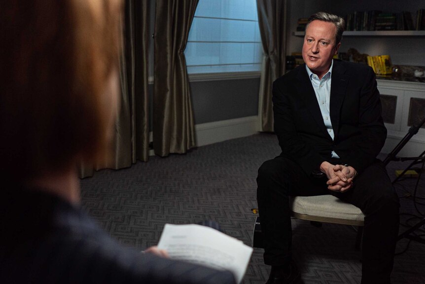 David Cameron sits on a chair.