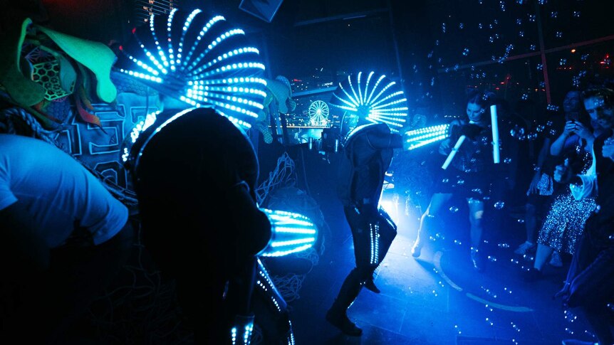 people in robot costumes dancing on the dancefloor with lights and bubbles