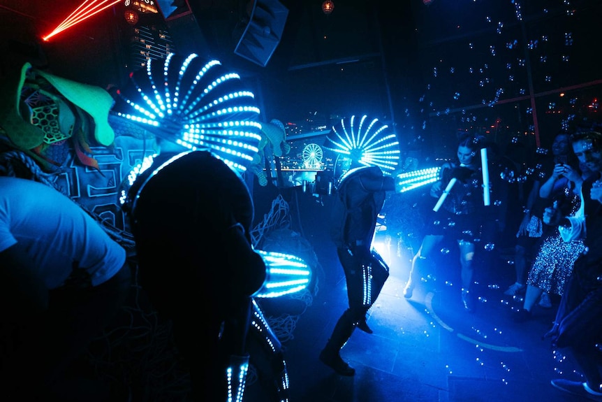people in robot costumes dancing on the dancefloor with lights and bubbles