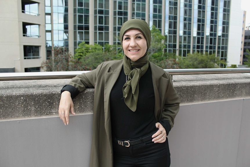 Halee Cosar leaning against a rail, with buildings in the background.