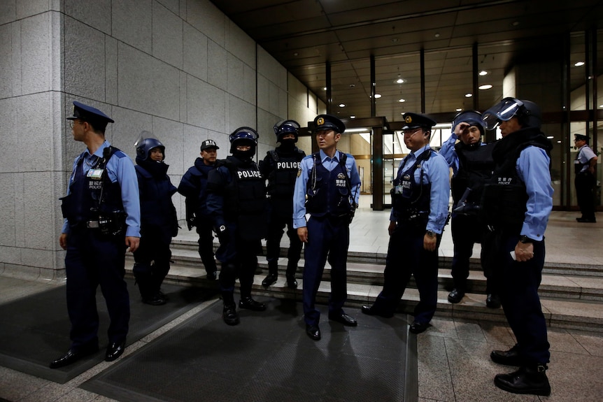 Police stand outside building.