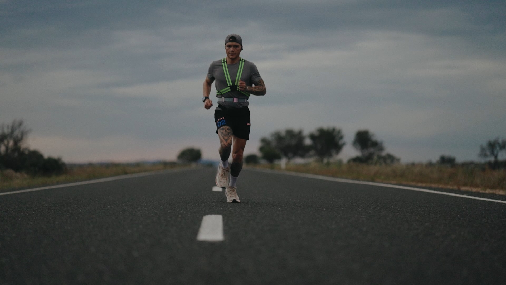 Jordan wears activewear and runs in the middle of an empty road.