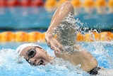 Female swimmer doing freestyle takes a breath. 