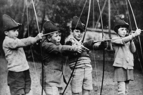 A group of young children with bow and arrows, wearing Robin Hood hats.
