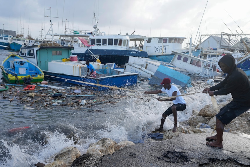 Fishermen pull a boat damaged by a hurricane