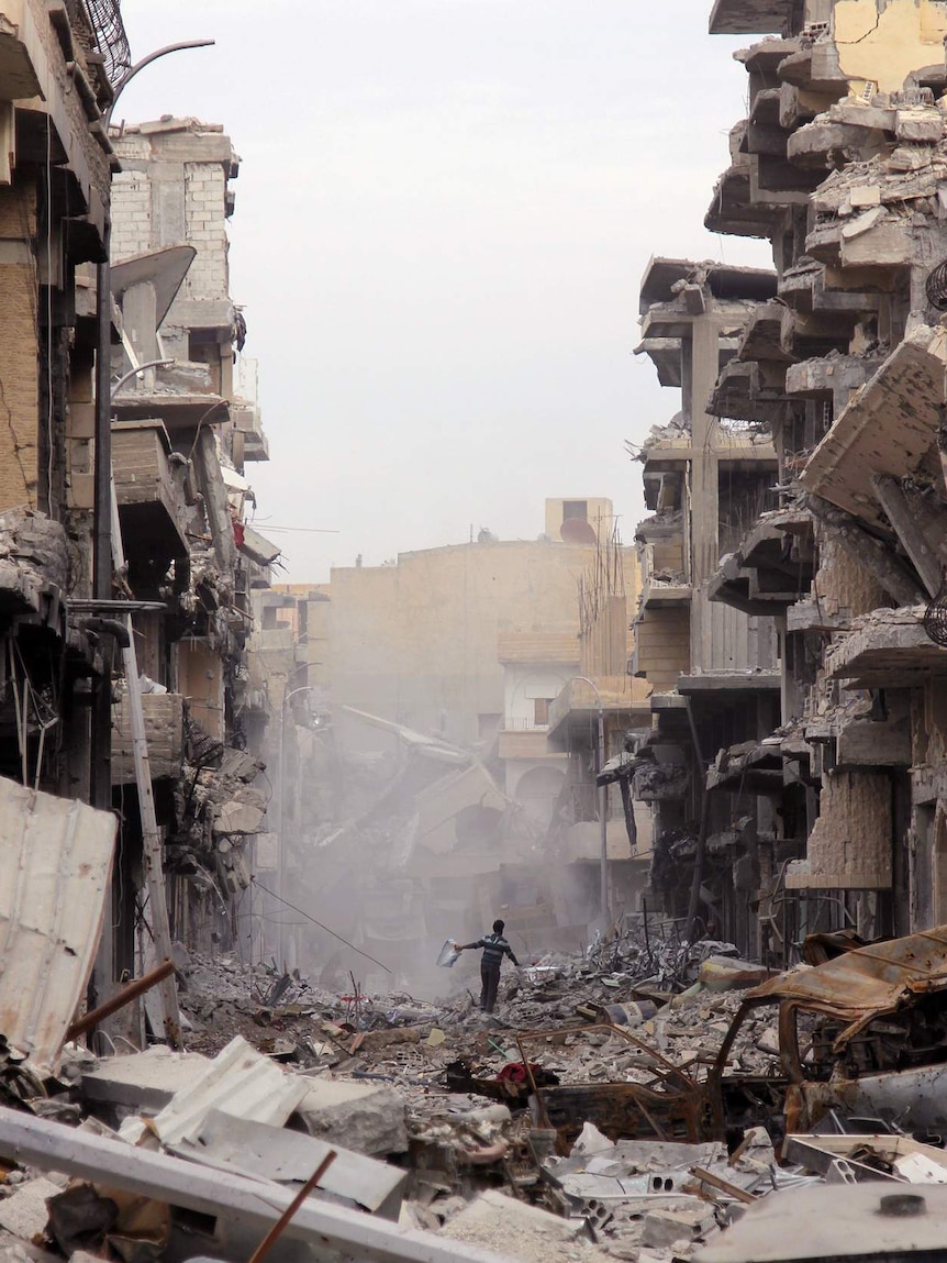 A Raqqa resident outside his home as a bulldozer clears the rubble, December 2017.