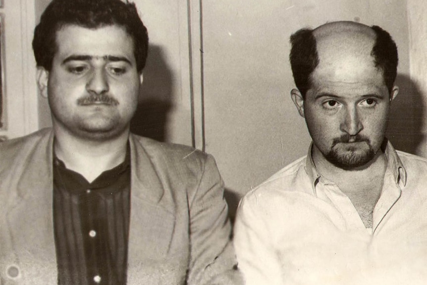 Two brothers with moustaches pose for a mugshot.