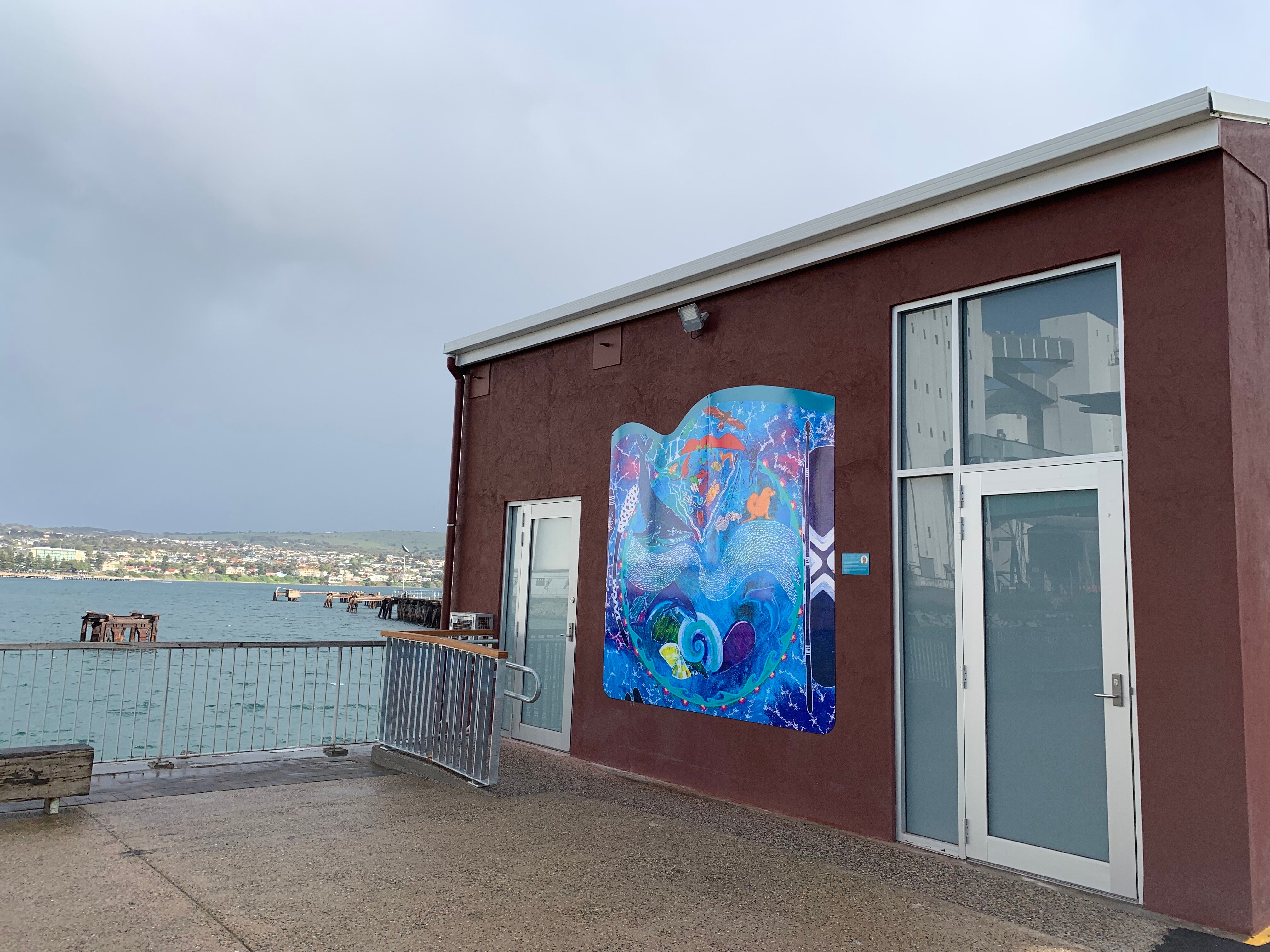 A small red tourism pop-up building with a beautiful blue aboriginal painting in the middle.