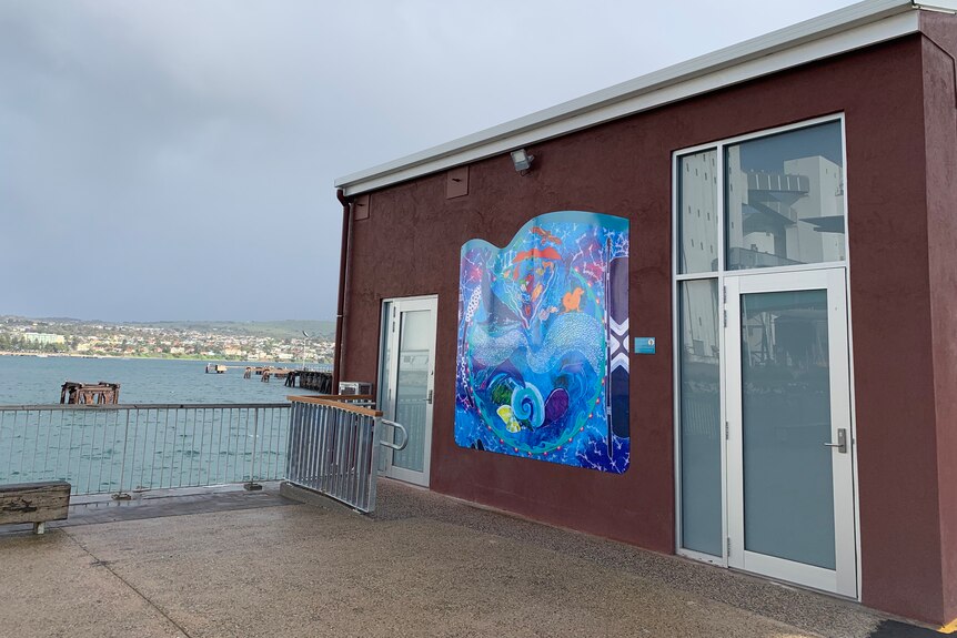 A small red tourism pop-up building with a beautiful blue aboriginal painting in the middle.