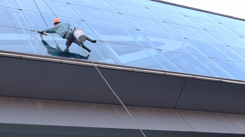 A man hangs off the side of a building while cleaning windows.