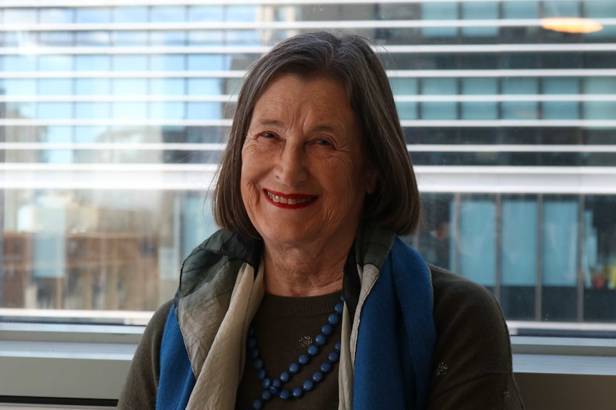 A woman wearing a blue scarf smiles for the camera.