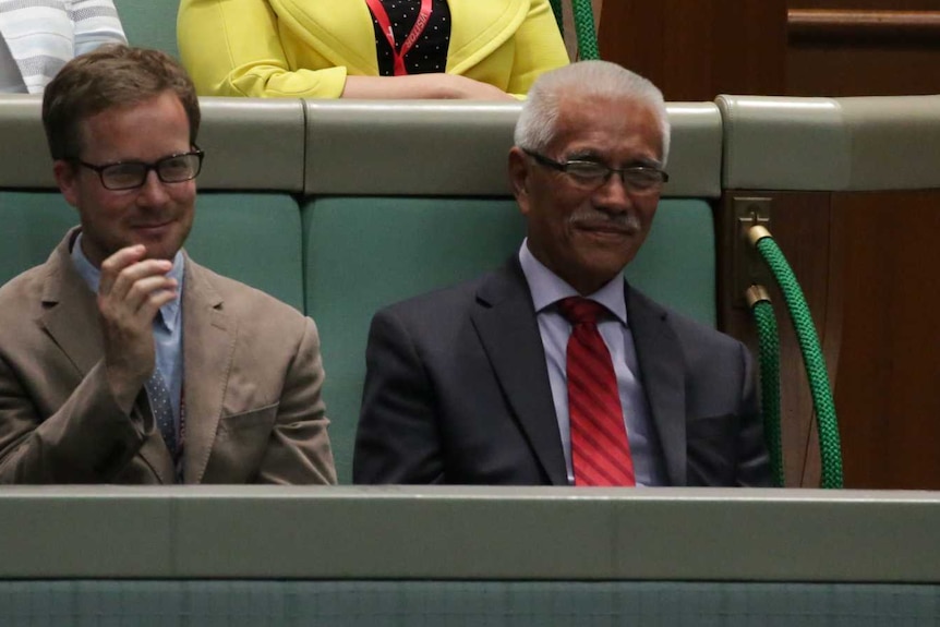 Mr Tong sits in the front row of the gallery, smiling.