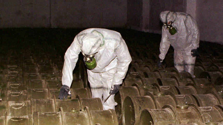 Russian military officers insoecting barrels of chemical weapons.