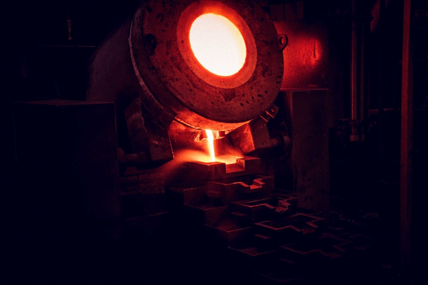 Furnace pours hot gold metal at gold mine.