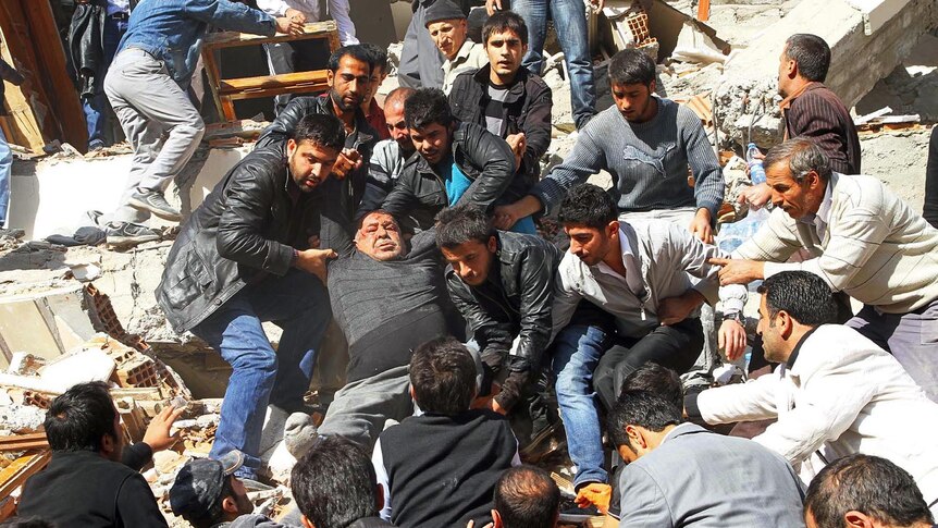 Desperate search: Men carry an injured man out of a collapsed building in Van.