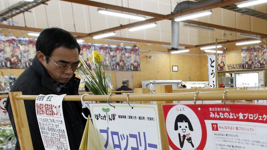 A Japanese shopper looks at empty vegetable shelves