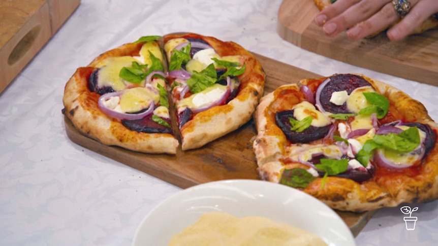 Homemade pizzas with vegetables, melted cheese and garnish on wooden cutting boards