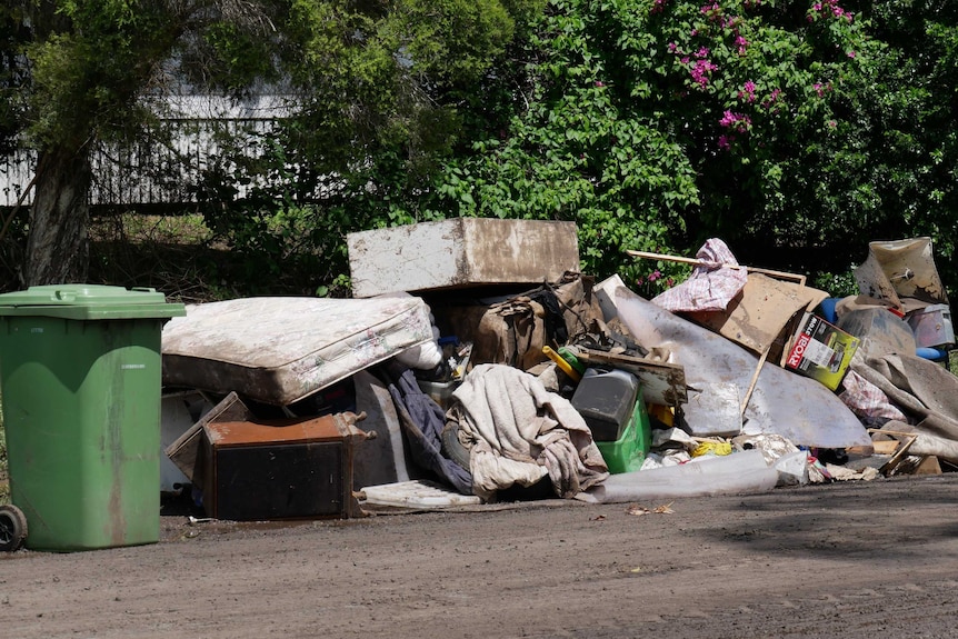 A pile of dirty and muddy furniture including mattresses and couches and boxes.