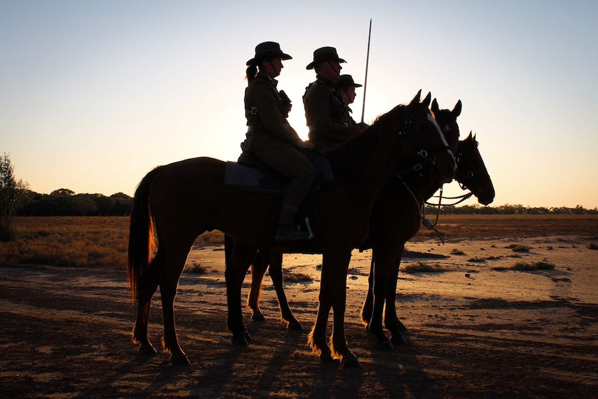 A silhouette of three mounted riders