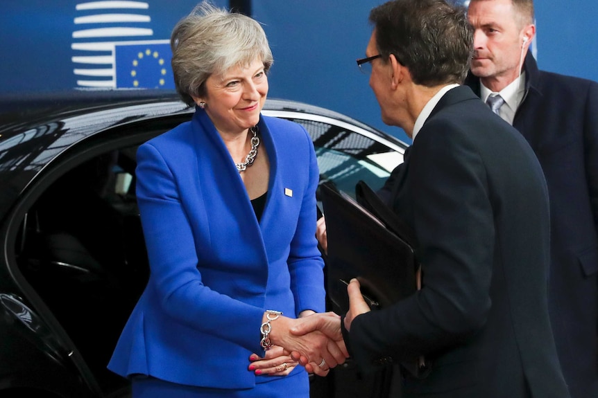 Theresa May shakes a man's hand after leaving a car