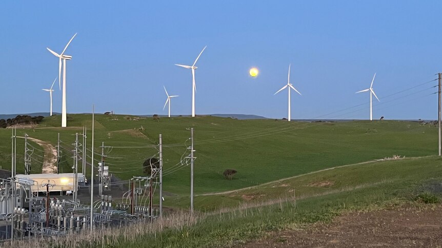 Wind turbines near electrical equipment with the moon behind