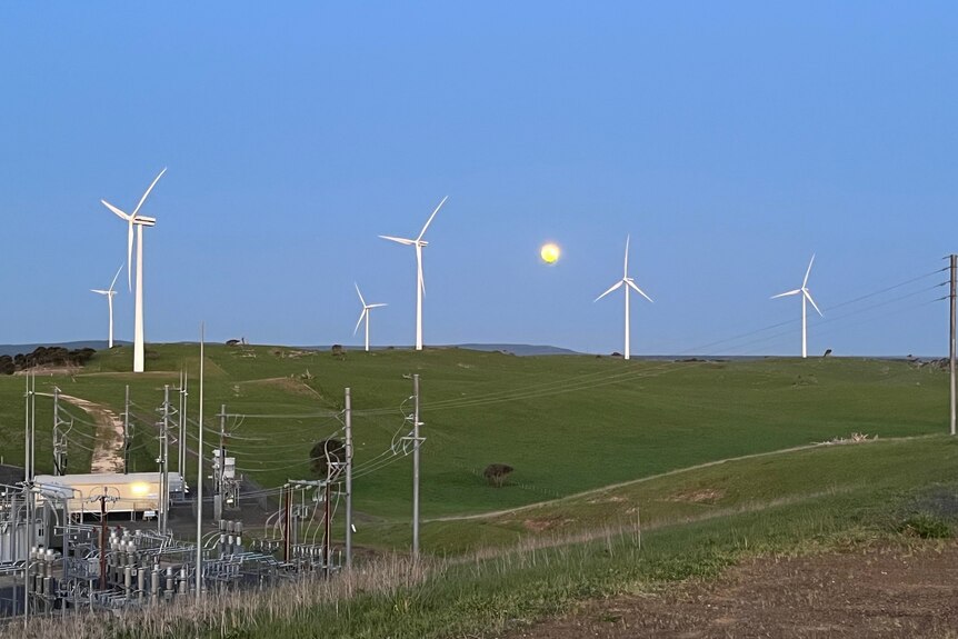 Wind turbines near electrical equipment with the moon behind