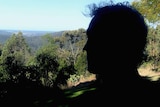 Silhouette of a man looking out toward trees in a backyard