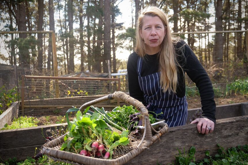 A woman in a garden with a basket full of vegetables.