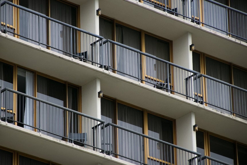 A close up of a row of balconies with sliding doors on a high rise building.