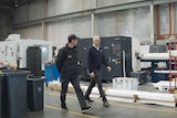 Two men walk through a factory.