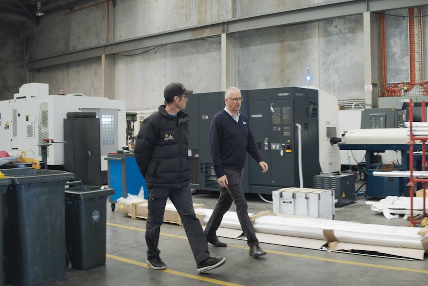 Two men walk through a factory.