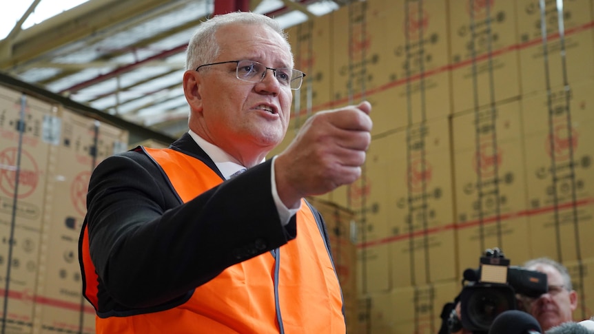 Scott Morrison, dressed in a suit and a high-vis vest, gesticulates as he speaks in a factory.