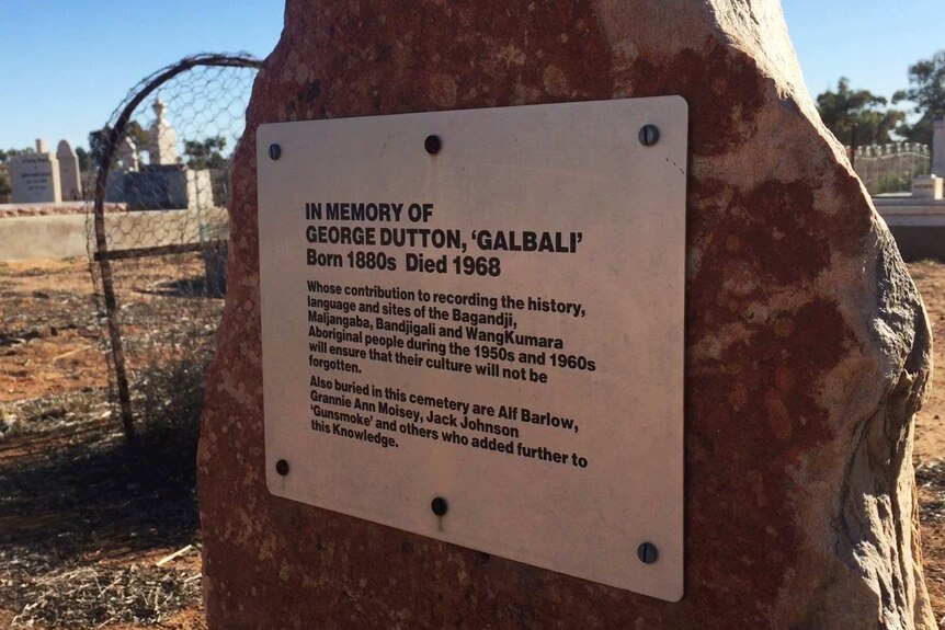 A plaque on a red rock reading: In memory of George Dutton, 'Galbali'. Born 1800s Died 1968.
