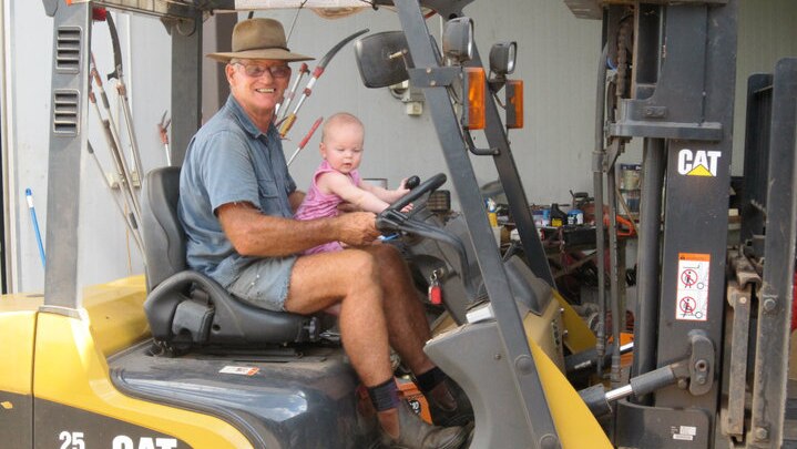 A man sits with a small child on a tractor
