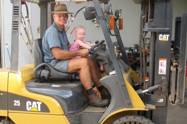 A man sits with a small child on a tractor