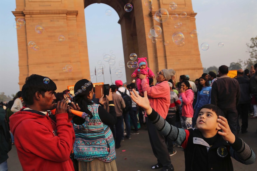 An Indian boy tries to catch soap water bubbles as people visit the India Gate war memorial in New Delhi.