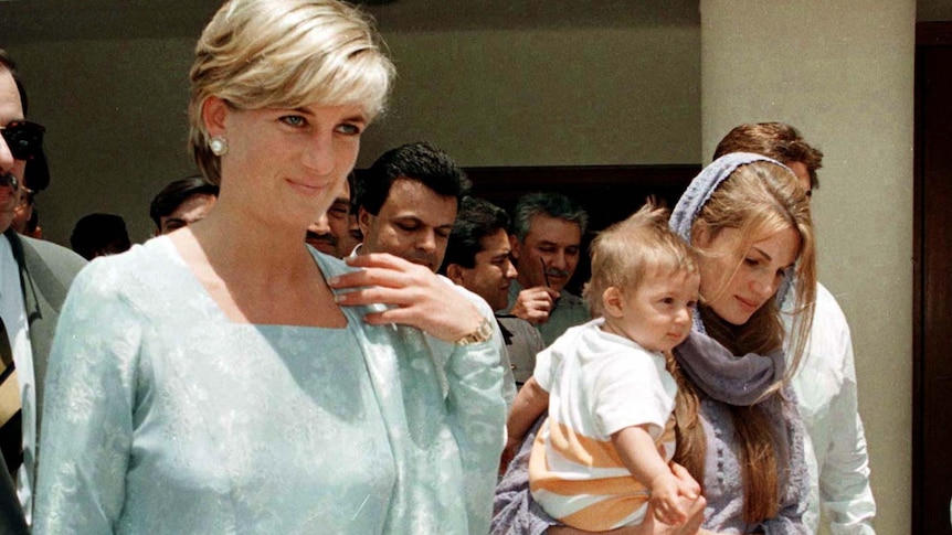 A historical photo of princess diana walking with her friend jemima khan. khan is carring a young child in her arms