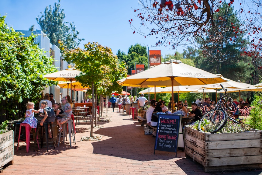 Sunny outdoor courtyard at Bright Brewery, groups of people sitting at outdoor tables with umbrellas